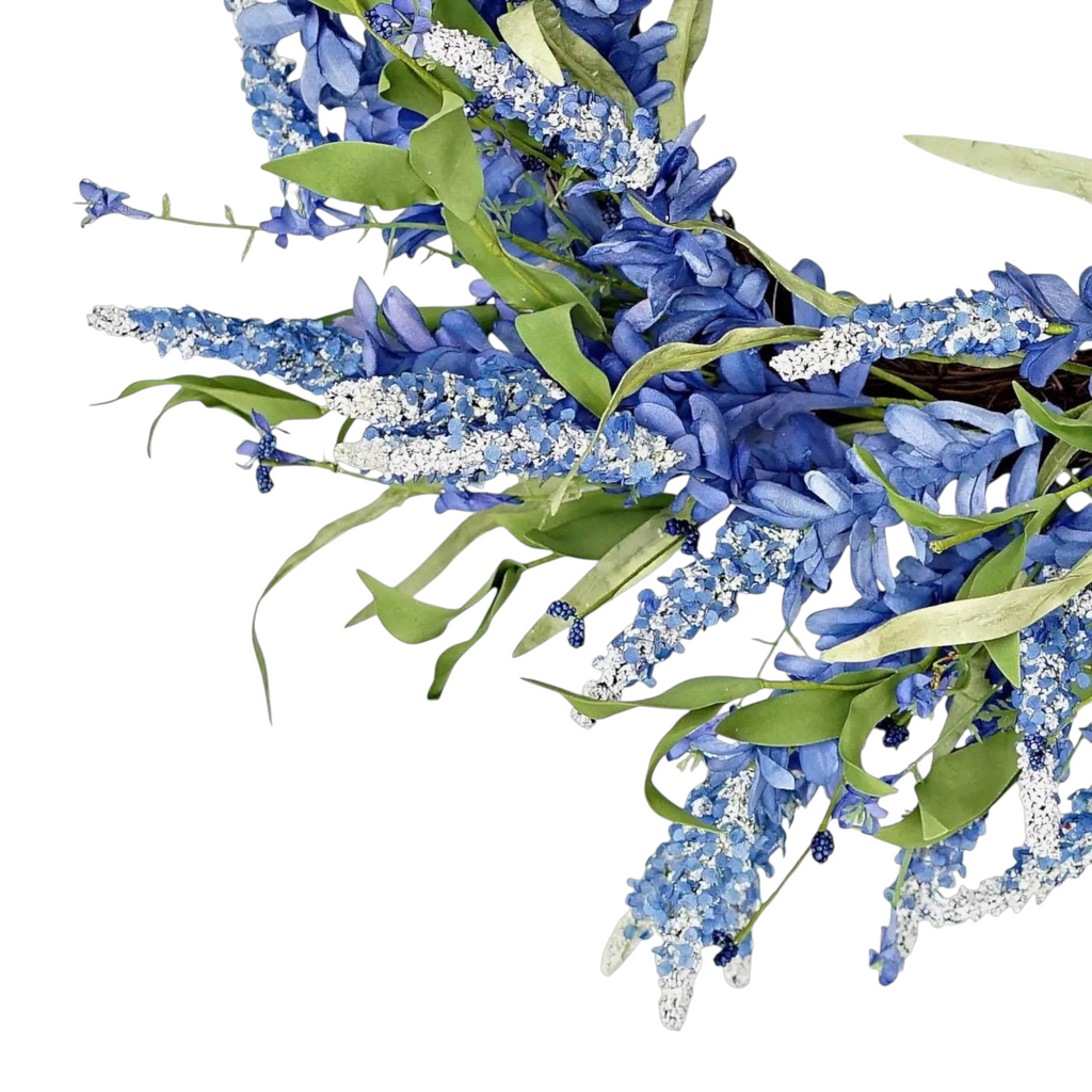 The Matthew John Collective 24-inch blue floral wreath featuring deep blue clusters and white-tipped botanical sprigs.