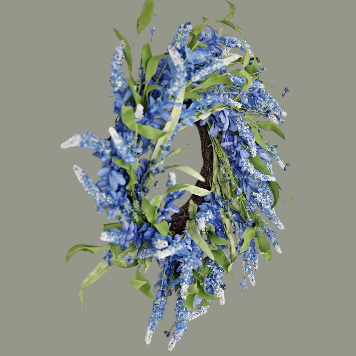 The Matthew John Collective 24-inch blue cluster flower wreath with lush green leaves on a rustic twig base