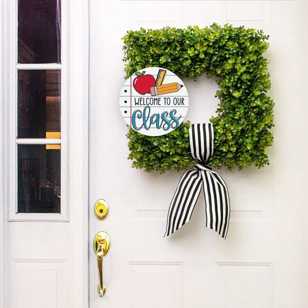 The Matthew John Collective round classroom sign featuring notebook paper design on a green boxwood wreath with bow.