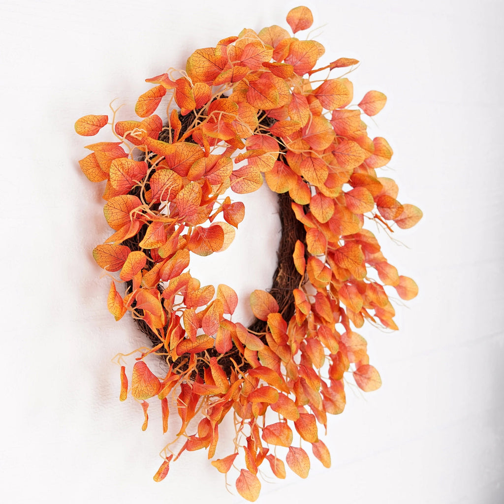 The Matthew John Collective 24-inch fall wreath with orange and yellow silk-screen silver dollar eucalyptus on twigs.