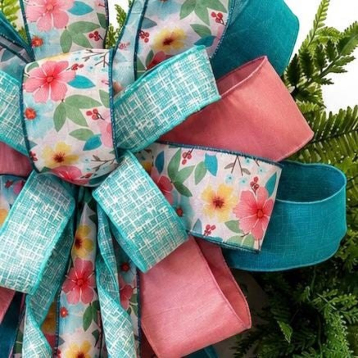 The Matthew John Collective Signature Seabreeze floral bow featuring teal, pink, and floral ribbons on a green wreath.