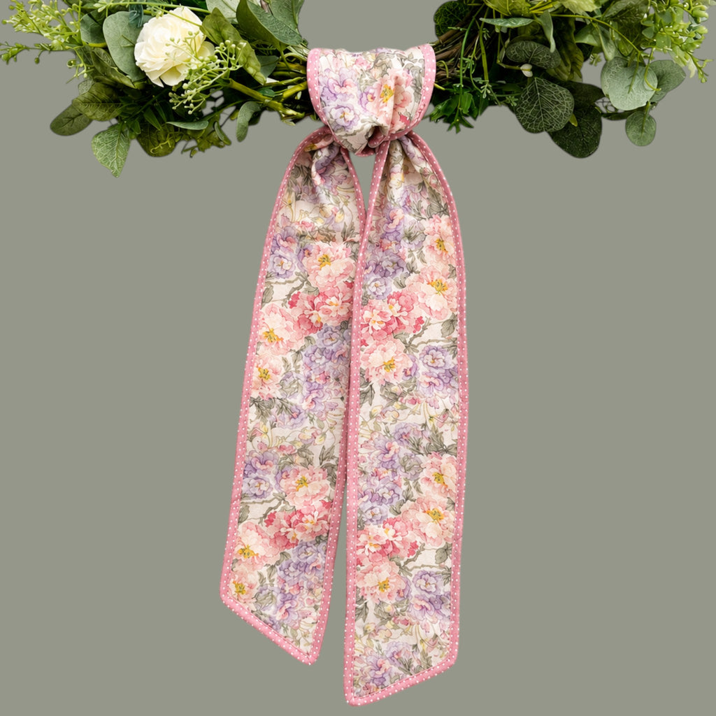 The Matthew John Collective D. Stevens floral wreath sash in pink and mauve with a polka dot backing on a green wreath
