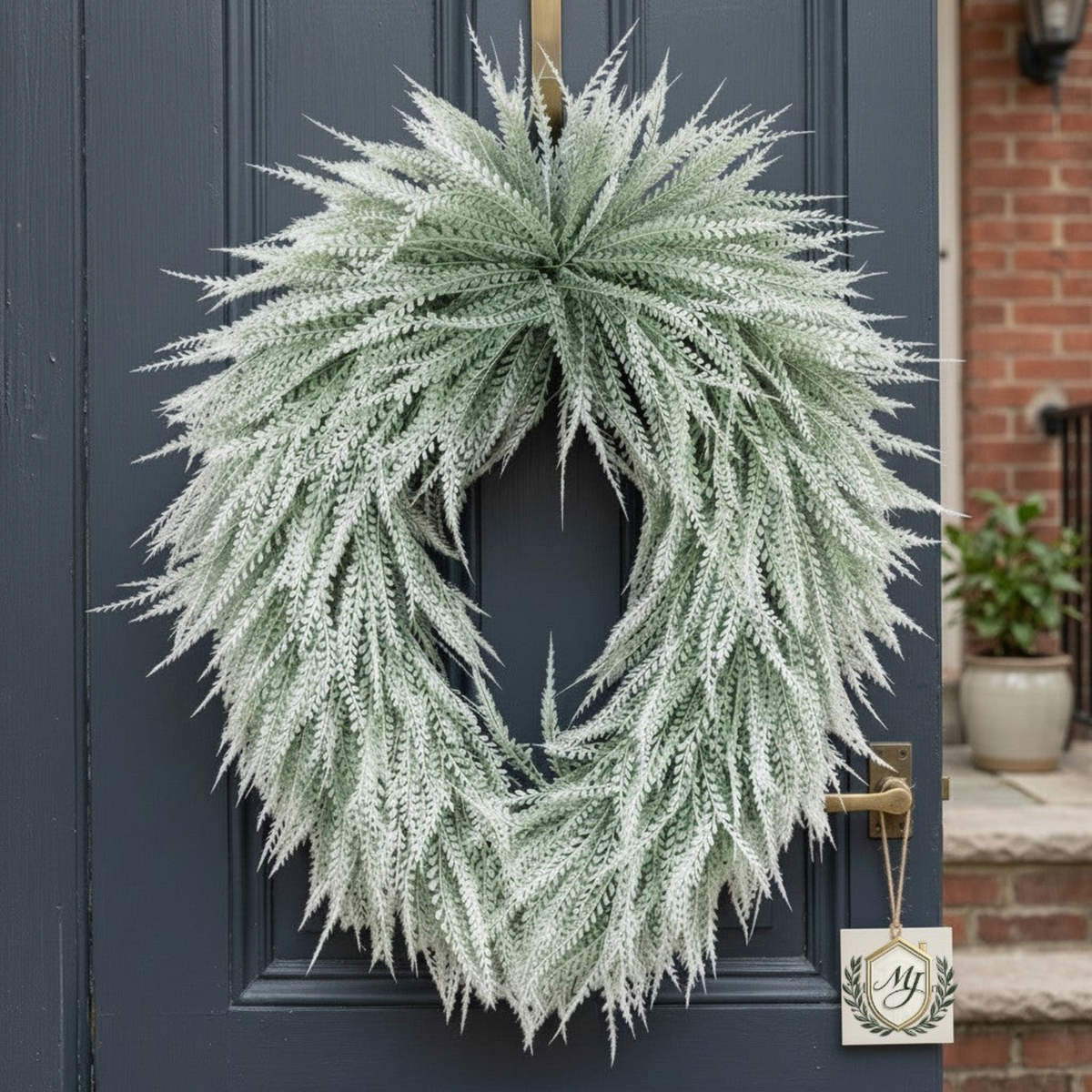 The Matthew John Collective frosted white bead grass oval wreath hanging on a dark blue front door