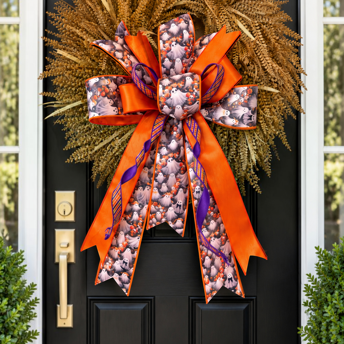 The Matthew John Collective oversized Halloween ghost and plaid wreath bow with long orange and purple ribbon tails.