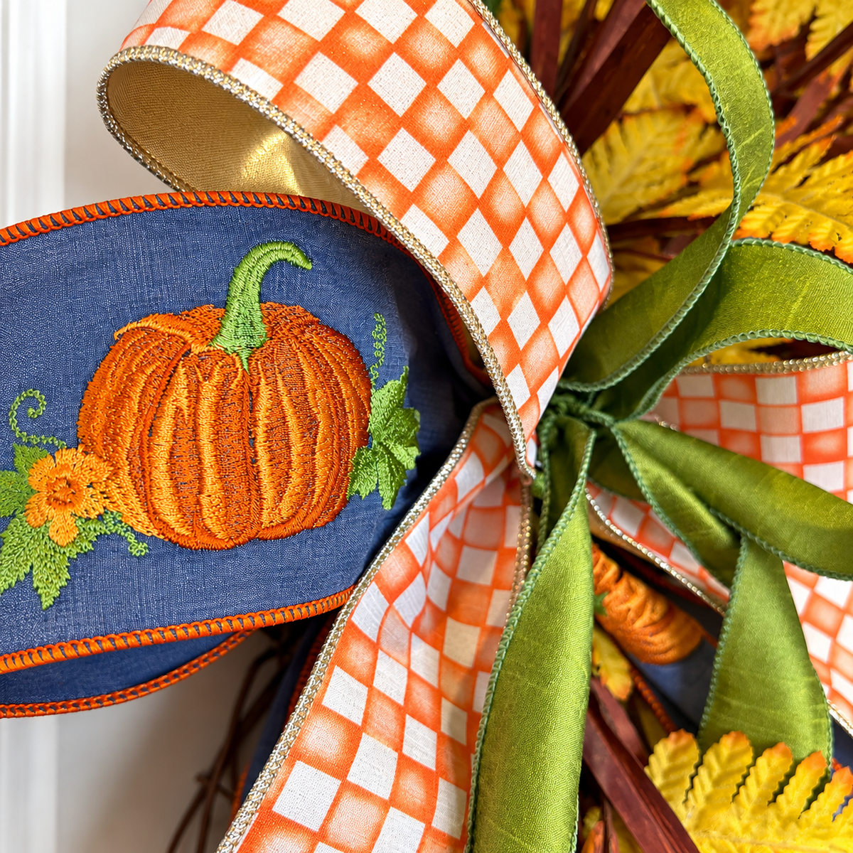 The Matthew John Collective Harvest Moon grapevine wreath featuring an embroidered pumpkin ribbon and orange gingham bow.
