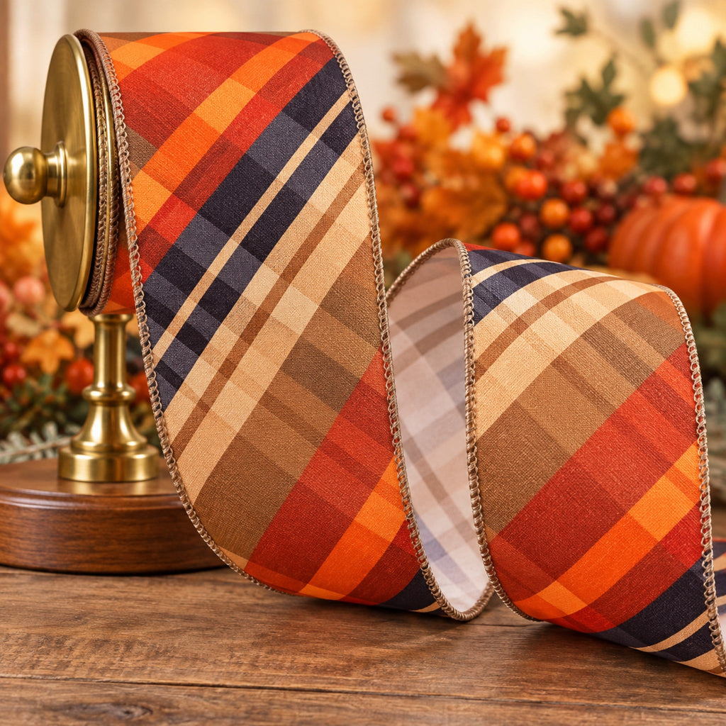 The Matthew John Collective diagonal plaid wired ribbon in autumn tones of orange, rust, navy, and brown on a spool.