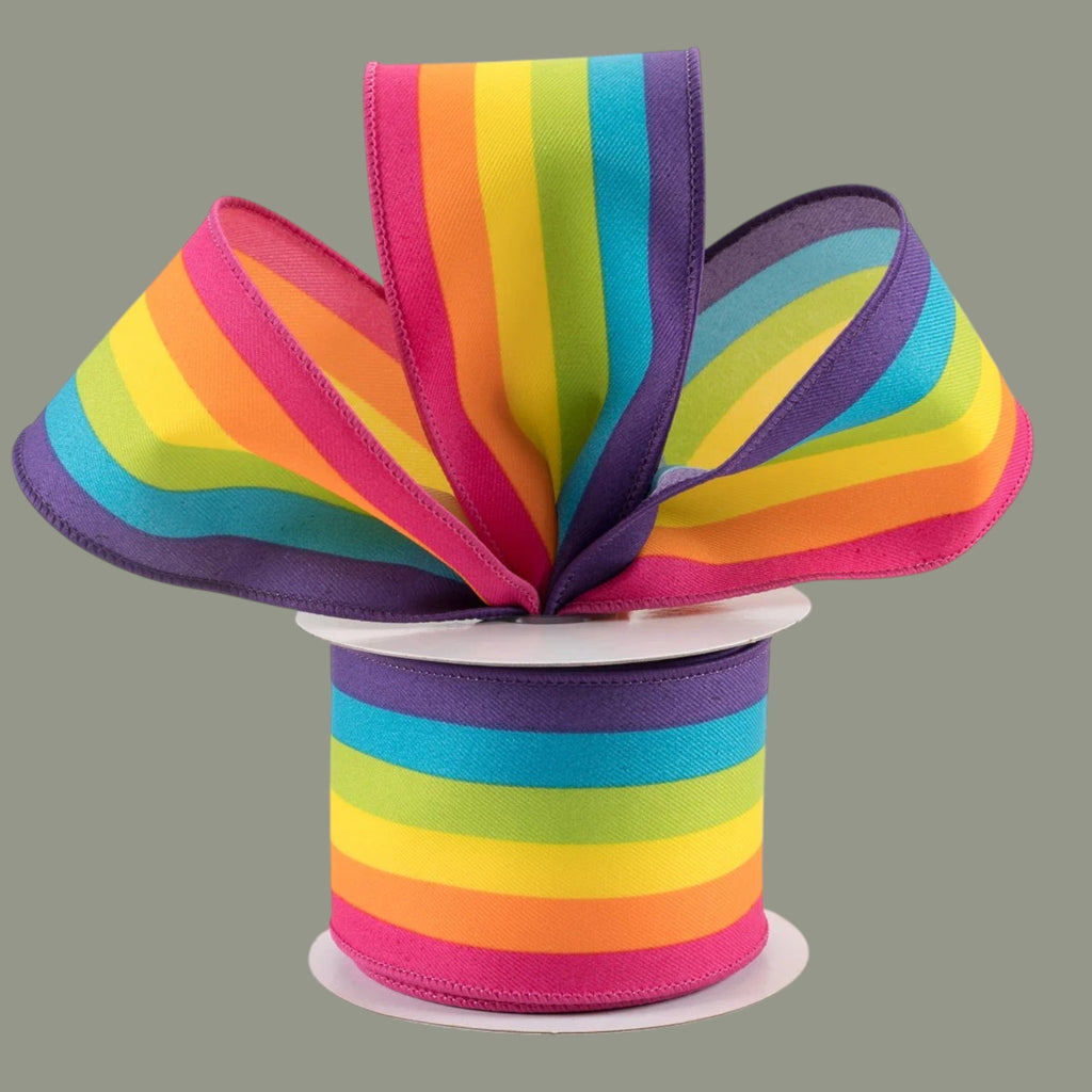 The Matthew John Collective rainbow vertical stripe wired ribbon on a spool with a decorative bow