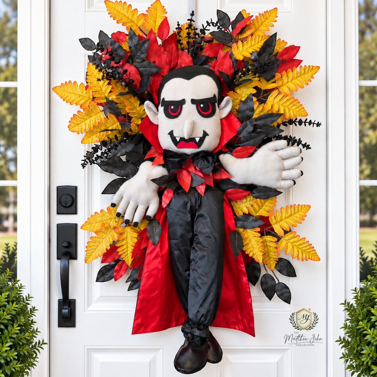 The Matthew John Collective vampire Halloween wreath with plush figure, red and black foliage, and golden fern sprays.