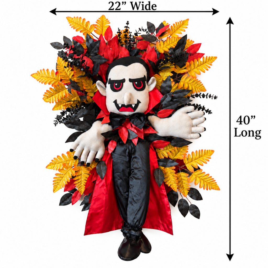 The Matthew John Collective vampire Halloween wreath with plush figure, red and black foliage, and golden fern sprays.