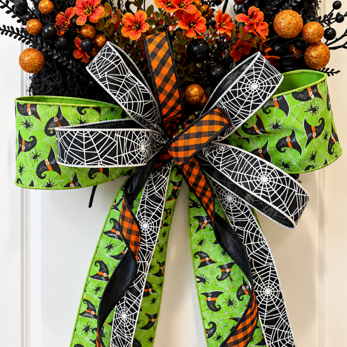 The Matthew John Collective Wicked Witch Halloween wreath featuring a large designer bow with green and spiderweb ribbon