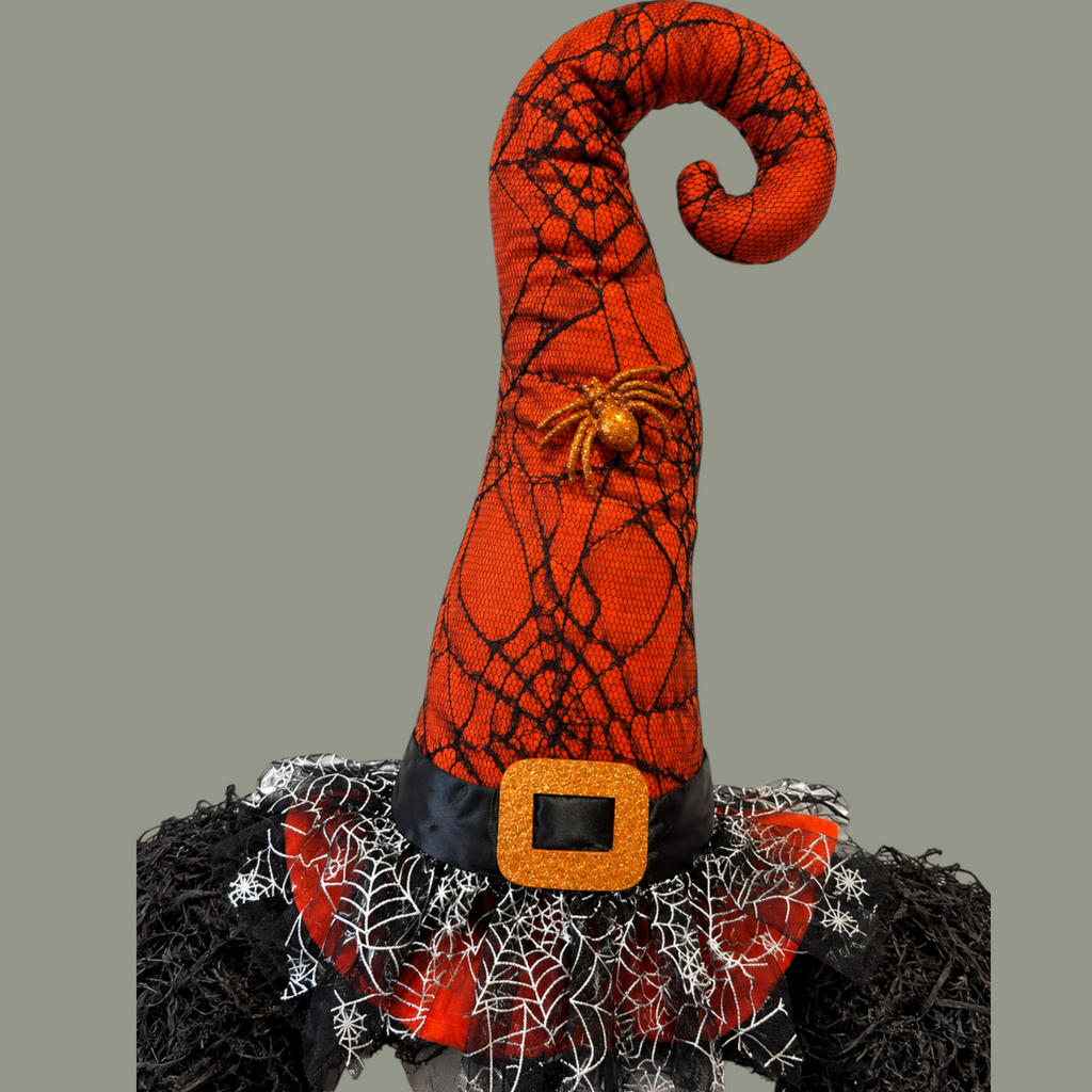 The Matthew John Collective Wicked Witch Halloween wreath featuring a curled orange spiderweb hat with a glitter spider